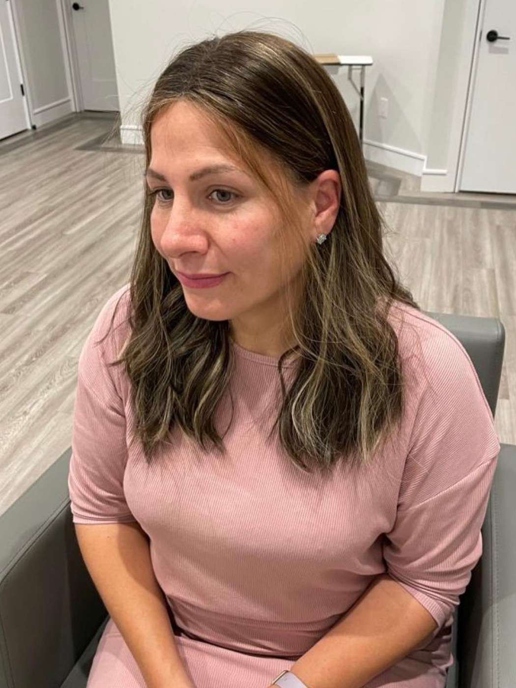 A client seated in a styling chair at the Miri salon, with the salon interior behind her.