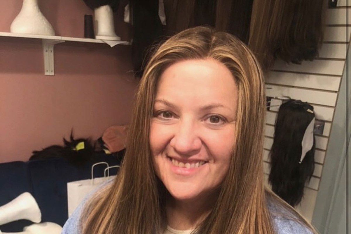 Straight hair with caramel highlights, in front of the wig shelves at the Miri salon.
