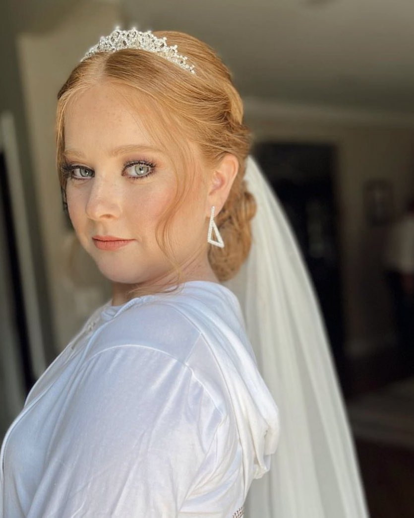 Bridal updo with a crystal tiara and veil, and loose curls framing the face.