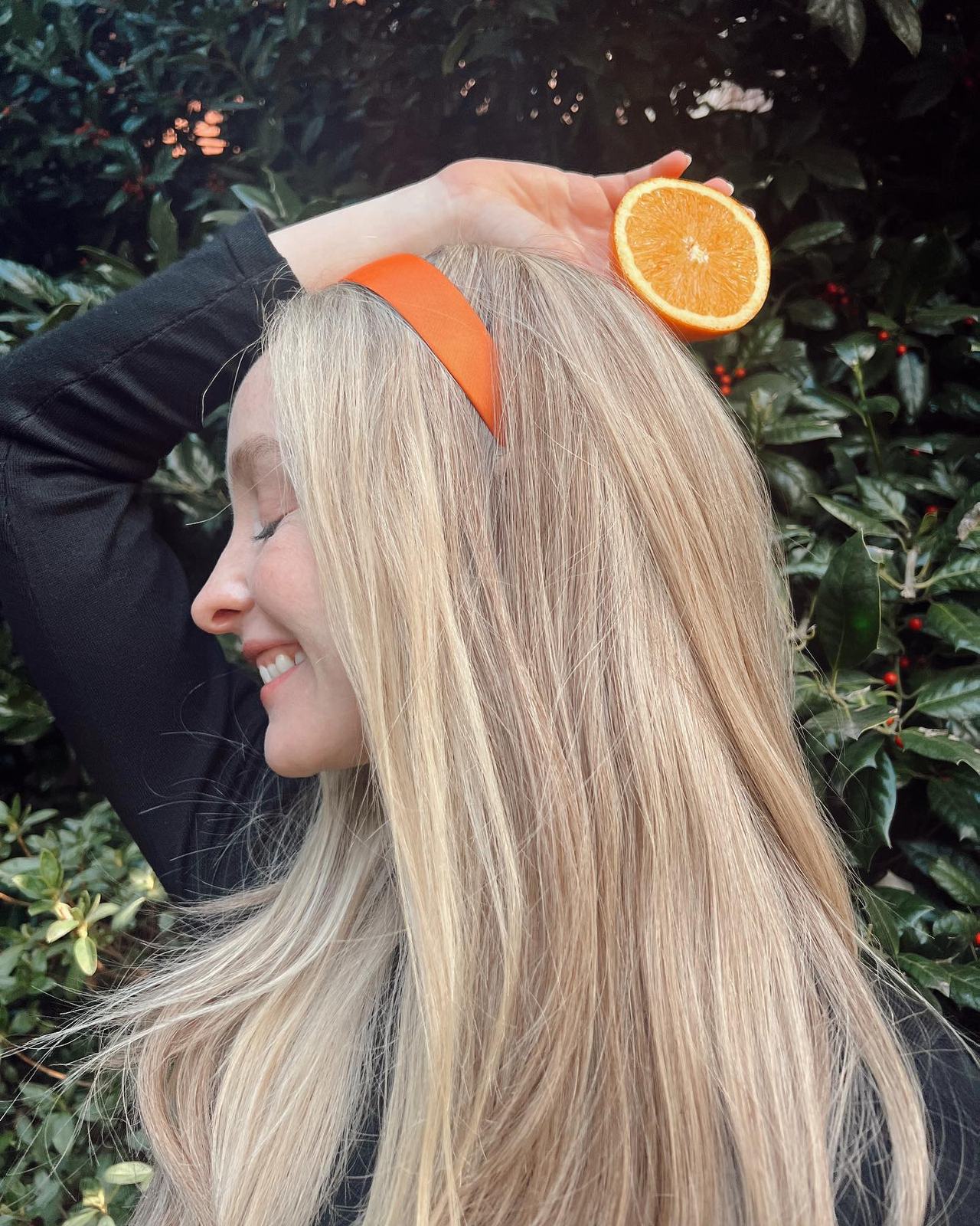 Long, straight blonde hair with a bright headband, worn with a white top.